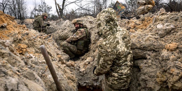 Ukrainian infantrymen take cover in a partially dug trench along the front line on March 5, 2023, outside of Bakhmut, Ukraine.