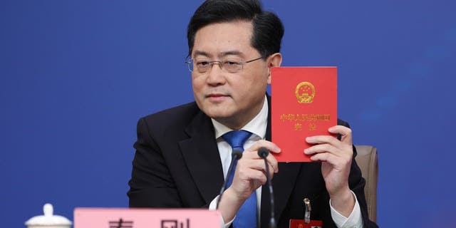 El Ministro de Relaciones Exteriores de China, Chen Gang, sostiene una constitución china durante una conferencia de prensa en el Centro de Medios.