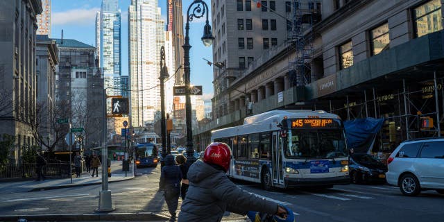 A bike messenger waits for a traffic light to change March 7, 2023, in downtown Brooklyn.