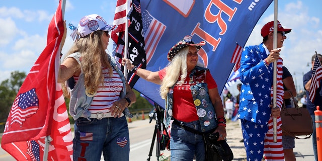 Trump supporters in cowgirl hats and an American flag suit near his Mar-a-Lago home March 21, 2023, in Palm Beach, Fla.