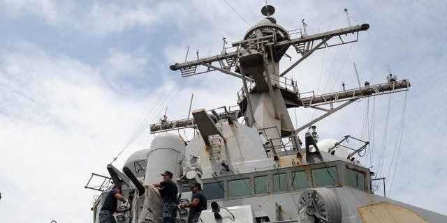 Los marineros de la Marina retiran la cubierta del sistema de armas Phalanx cerca del USS Milius (DDG-69), un barco destructor de misiles guiados de múltiples misiones atracado en el puerto sur de Manila el 18 de agosto de 2012.