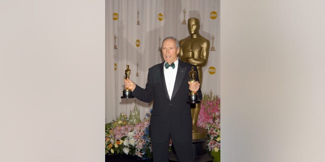 Clint Eastwood in a tuxedo holding his Oscars for 