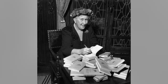 British mystery author Agatha Christie (1890-1976) autographs French editions of her books, circa 1950. 
