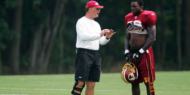 El apoyador de Washington LaVar Arrington habla con el entrenador de apoyadores Dale Lindsey durante el campamento de entrenamiento en Ashburn, Virginia, el 4 de agosto de 2004.