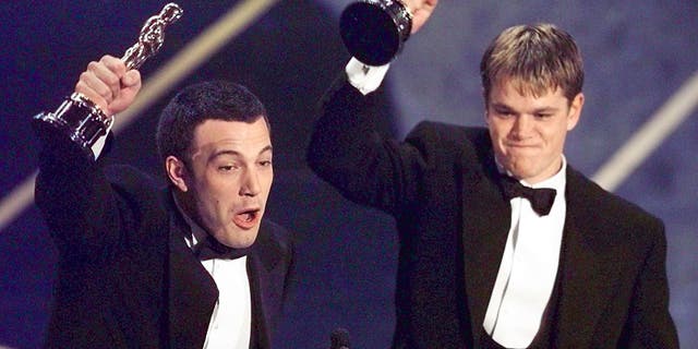 Ben Affleck, left, and Matt Damon hold up their Oscars after winning in the Original Screenplay Category during the 70th Academy Awards.