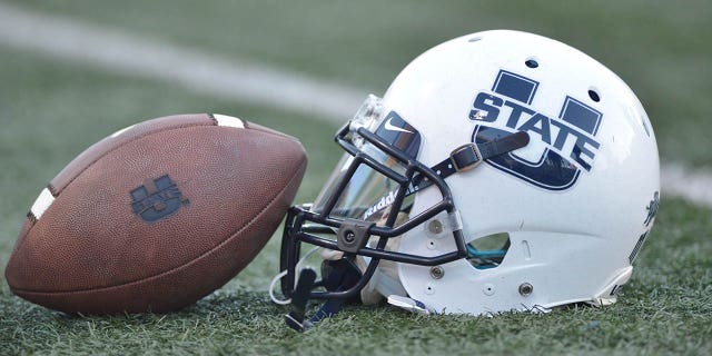 Un casco y una pelota de fútbol de los Utah State Aggies antes del comienzo de un partido entre los Fresno State Bulldogs y los Utah Aggies.