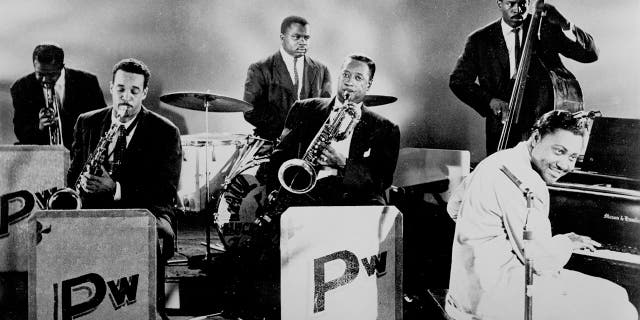 R&B pianist and singer Amos Milburn with Paul Williams (baritone sax, center), Eddie Silver (tenor sax, left), Jimmy Brown (trumpet), Belton Evans (drums), and Steve Cooper (bass), circa 1950. Paul Williams, performing with the Hucklebuckers, co-headlined with guitarist Tiny Grimes the first rock concert in Cleveland on March 21, 1952.