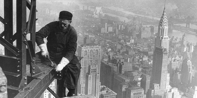 A construction worker bolts beams during construction of the Empire State Building, New York City, circa 1930. In the background (right) is the Chrysler Building. 