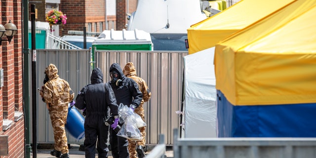 Emergency workers in protective suits search an area after a man and woman were exposed to the Novichok nerve agent on July 6, 2018, in Salisbury, England.