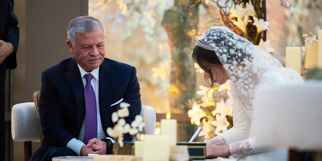 King of Jordan Abdullah II watches as his daughter signs the wedding document during the ceremony.