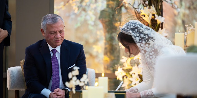 King of Jordan Abdullah II watches as his daughter signs the wedding document during the ceremony.
