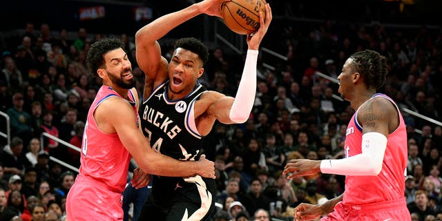 Milwaukee Bucks forward Giannis Antetokounmpo is fouled by Washington Wizards forward Anthony Gill, left, during the first half of an NBA basketball game, Sunday, March 5, 2023, in Washington. , DC Wizards guard Delon Wright is on the right.