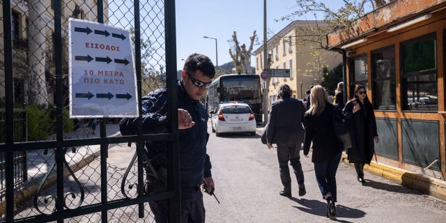 A Greek police officer closes the entrance of the courthouse following the transfer of suspects that have been charged with membership in a terrorist organization, in Athens, on March 2023.