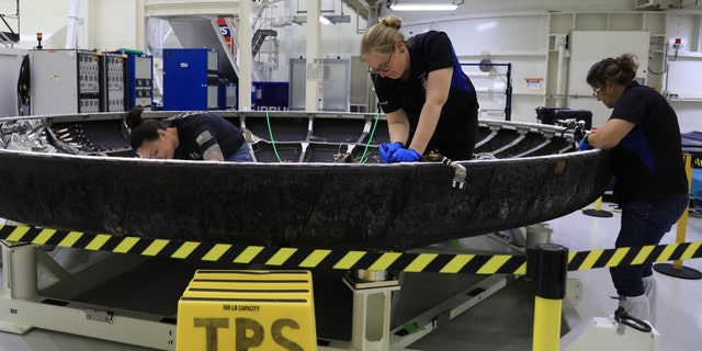 As part of the post-flight analysis, technicians inspect Orion's heat shield. 