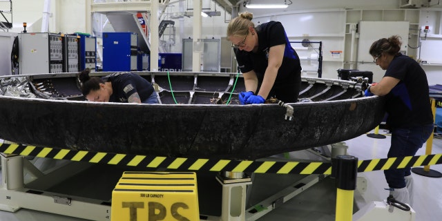 As part of the post-flight analysis, technicians inspect Orion's heat shield. 