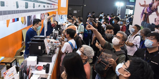 People wearing face masks buy solid-state drives (SSDs) during the Hong Kong Computer and Communications Festival 2021 at the Hong Kong Convention and Exhibition Center in Hong Kong, China, Aug. 20, 2021.