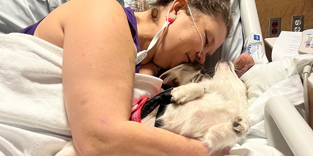 Adkins cuddles her dog Mazi in a hospital bed after a recent procedure.