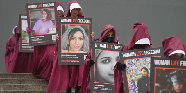 Activistas sosteniendo pancartas que leen en él "Mujer, vida, libertad." Fotografías de mujeres asesinadas en Irán, durante una manifestación para celebrar el Día Internacional de la Mujer, en Londres, el 8 de marzo de 2023.