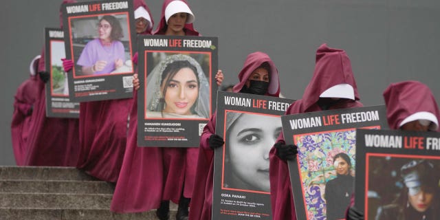 Activists hold placard reading "Woman, Life, Freedom" with portraits of women killed in Iran, during an International Women's Day demonstration, in London on March 8, 2023.