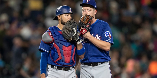 Texas Rangers catcher Isiah Kiner-Falefa and starting pitcher Adrian Sampson stand on the pitcher's mound during a game against the Seattle Mariners at Safeco Field on September 29, 2018 in Seattle.