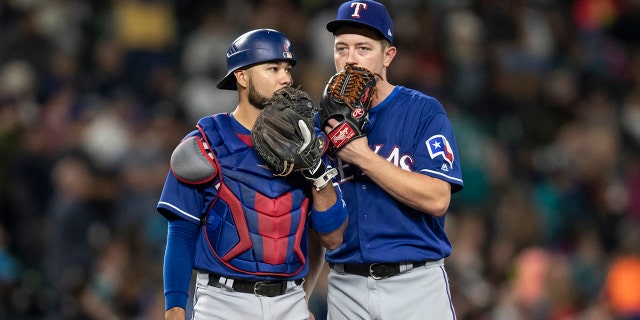 Catcher Isiah Kiner-Falefa and starting pitcher Adrian Sampson of the Texas Rangers meet at the pitcher's mound during a game against the Seattle Mariners at Safeco Field Sept. 29, 2018, in Seattle.