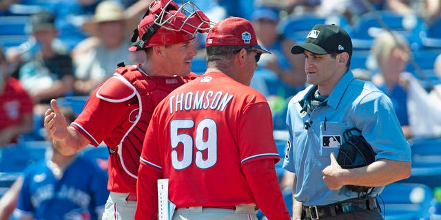 El receptor abierto de los Philadelphia Phillies, JT Realmuto, y el manager Rob Thomson discuten con el árbitro Randy Rosenberg después de que Realmuto fuera expulsado de un juego de béisbol de entrenamiento de primavera en Dunedin, Florida, el lunes 27 de marzo de 2023.