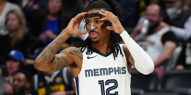 Memphis Grizzlies guard Ja Morant adjusts his face guard during the Nuggets game at Ball Arena in Denver on March 3, 2023.