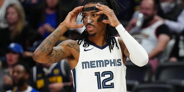 Penjaga Memphis Grizzlies Ja Morant menyesuaikan pelindung wajahnya selama pertandingan Nuggets di Ball Arena di Denver pada 3 Maret 2023.