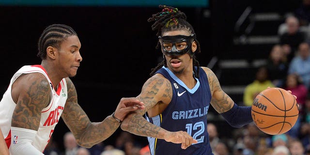 Memphis Grizzlies guard Ja Morant, #12, handles the ball against Houston Rockets guard Kevin Porter Jr., #3, in the second half of an NBA basketball game Wednesday, March 22, 2023, in Memphis, Tennessee.