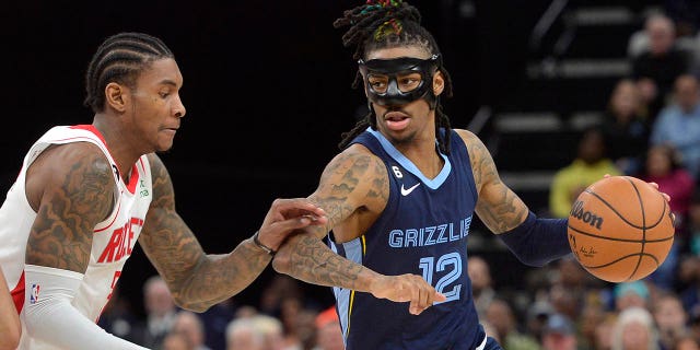 Memphis Grizzlies guard Ja Morant, #12, handles the ball against Houston Rockets guard Kevin Porter Jr., #3, in the second half of an NBA basketball game Wednesday, March 22, 2023, in Memphis, Tennessee.