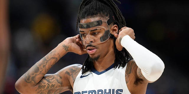 Memphis Grizzlies guard Ja Morant adjusts his protective mask before shooting a pair of free throws against the Nuggets on Friday, March 3, 2023, in Denver.