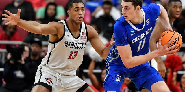 El centro de Creighton, Ryan Kalkbrenner (11), mueve el balón contra el alero de San Diego State, Jaedon LeDee (13), en la primera mitad de un partido de baloncesto universitario Elite 8 en la Región Sur del Torneo de la NCAA, el domingo 26 de marzo de 2023, en Louisville, EE. Kentucky.