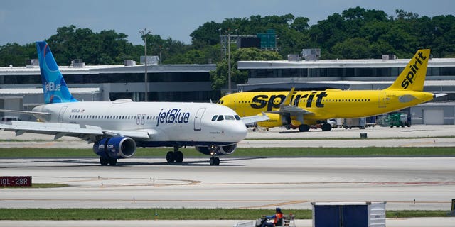 JetBlue's Airbus A320, left, passes a Spirit Airlines Airbus A320 as it taxis on the runway, July 7, 2022, at Fort Lauderdale-Hollywood International Airport in Fort Lauderdale, Florida.