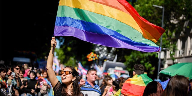 Une femme lors d'un défilé de la fierté LGBTQ, brandissant un drapeau arc-en-ciel.