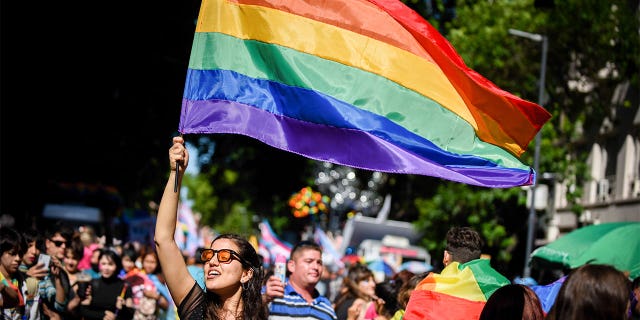 Une femme lors d'un défilé de la fierté LGBTQ, brandissant un drapeau arc-en-ciel.