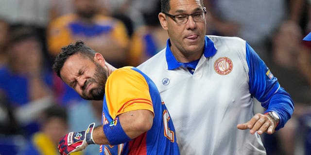 José Altuve of Venezuela is helped by a coach after he was struck by a pitch during the fifth inning of a World Baseball Classic game against the USA on March 18, 2023, in Miami.