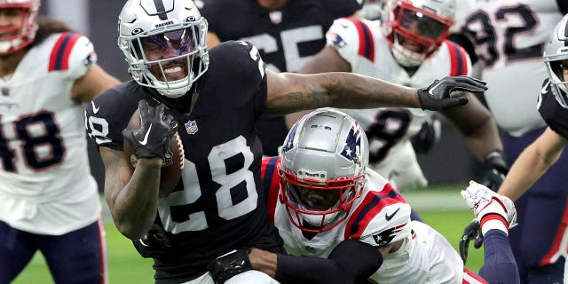 Jonathan Jones, #31 of the New England Patriots, tackles Josh Jacobs, #28 of the Las Vegas Raiders, during the first quarter of the game at Allegiant Stadium on December 18, 2022 in Las Vegas.