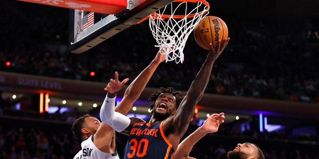 New York Knicks forward Julius Randle (30) drives to the basket against Minnesota Timberwolves forward Kyle Anderson (5) and center Rudy Gobert (27) during the second half of an NBA basketball game, Monday, March 20, 2023, in New York.