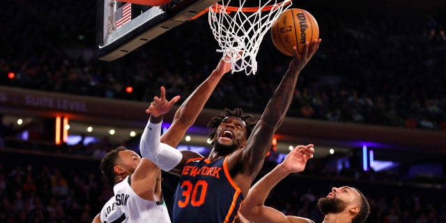 El alero de los New York Knicks Julius Randle (30) se dirige a la canasta contra el alero de los Minnesota Timberwolves Kyle Anderson (5) y el centro Rudy Gobert (27) en la segunda mitad de un partido de baloncesto de la NBA el lunes 20 de marzo de 2023 en Nueva York.