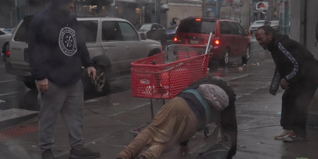 Frank Rodriguez stands over an addict struggling to stay on his feet.
