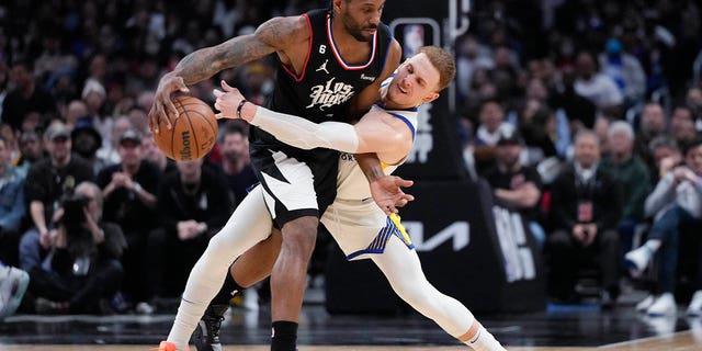 Kawhi Leonard of the Los Angeles Clippers, left, dribbles the ball as Donte DiVincenzo of the Golden State Warriors defends during the second half of an NBA basketball game Wednesday, March 15, 2023, in Los Angeles.