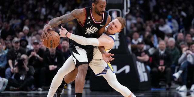 Los Angeles Clippers' Kawhi Leonard, left, dribbles the ball as Golden State Warriors' Donte DiVincenzo defends during the second half of an NBA basketball game Wednesday, March 15, 2023, in Los Angeles.