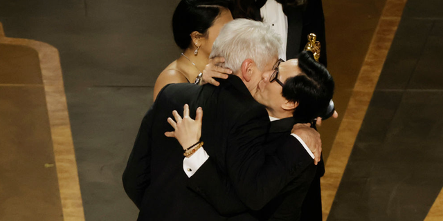 Ke Huy Quan accepts the award for Best Picture for "Everything Everywhere All at Once" from Harrison Ford onstage during the 95th Annual Academy Awards.