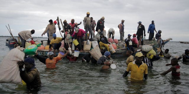 Fishermen swim out from an incoming boat at a berth, some with their overnight catch in Kwale county, Gazi Bay, Kenya, on June 12, 2022.