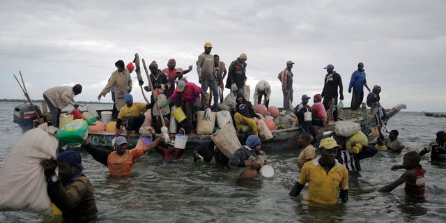 Nelayan berenang keluar dari perahu yang datang di dermaga, beberapa dengan hasil tangkapan semalam di daerah Kwale, Teluk Gazi, Kenya, pada 12 Juni 2022.
