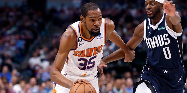Kevin Durant (35) of the Phoenix Suns goes to the basket as Justin Holiday (0) of the Dallas Mavericks defends in the second half of a game at American Airlines Center March 5, 2023, in Dallas. The Suns won 130-126. 