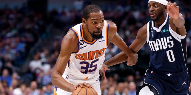 Kevin Durant (35) of the Phoenix Suns goes to the basket as Justin Holiday (0) of the Dallas Mavericks defends in the second half of a game at the American Airlines Center on March 5, 2023 in Dallas.  The Suns won 130-126. 