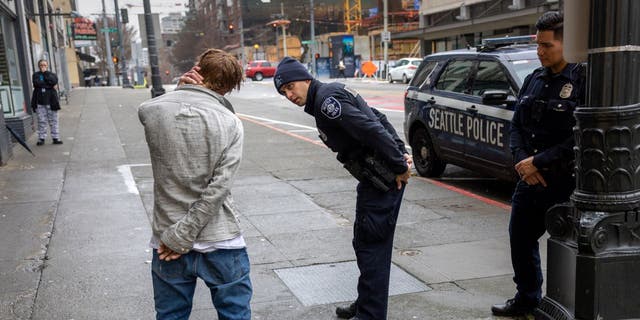 Police officers check on a man who said he has been smoking fentanyl in downtown Seattle on March 14, 2022 in Seattle, Washington. Use of the powerful opioid has surged in the last several years, especially in Seattle's large homeless community. According to a recent report commissioned by Seattle Councilmember Andrew Lewis, the COVID-19 pandemic put undue pressure on the city's shelter system and delayed funds for new housing, leading to an increase in homelessness. 