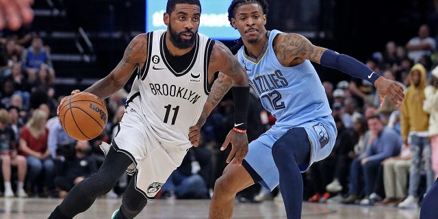 Kyrie Irving of the Brooklyn Nets goes to the basket against Ja Morant of the Grizzlies at FedExForum on Oct. 24, 2022, in Memphis, Tennessee.