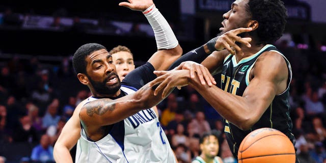 Dallas Mavericks guard Kyrie Irving and Hornets center Mark Williams battle for the ball in Charlotte, North Carolina, Sunday, March 26, 2023.